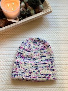 a knitted hat sitting on top of a table next to a candle and some rocks