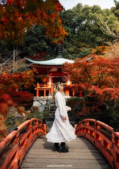 a woman standing on a bridge in front of trees