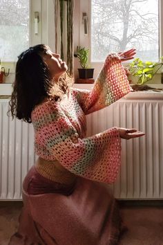 a woman sitting on the floor in front of a radiator next to a window