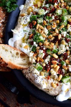 a pizza topped with lots of toppings on top of a plate next to bread