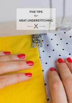 a woman's hands with red nail polish on top of a yellow piece of fabric