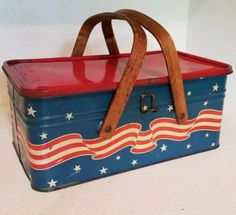 an old tin lunch box with stars and stripes painted on the side, holding a wooden handle