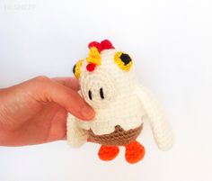 a hand holding a small crocheted chicken