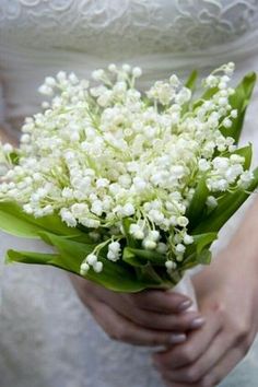 a person holding a bouquet of white flowers in their left hand and wearing a wedding dress