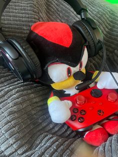 a stuffed animal with headphones on laying next to a nintendo wii controller and game controller