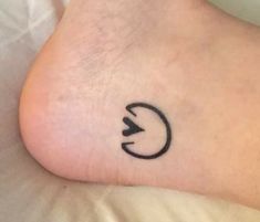 a small tattoo on the foot of a person's left leg, with an arrow in the middle