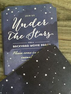 the under the stars movie party is set up on top of a wooden table with black paper