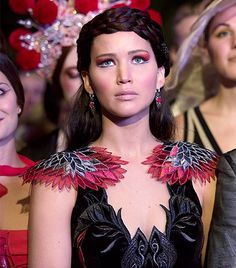 a woman in a black dress with red flowers on her chest and other women behind her