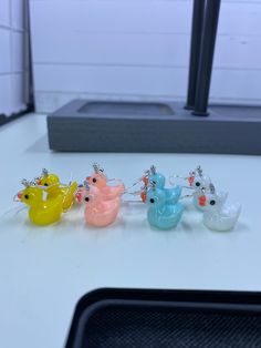 five small plastic birds sitting on top of a white table next to a black object