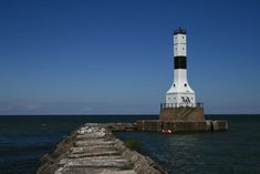 a light house sitting on top of a pier next to the ocean in front of a boat