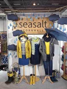 an assortment of clothing and umbrellas on display in a store window with the words seasalt cornwall