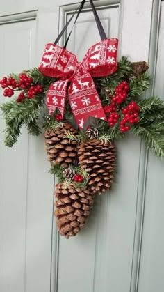 a pine cone hanging from the side of a door decorated with red berries and evergreen cones