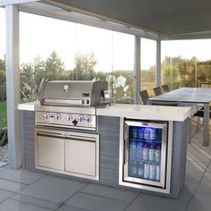 an outdoor kitchen with stainless steel appliances and seating area, overlooking a large open patio