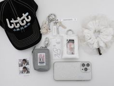 an assortment of personal items laid out on top of a white surface, including a cell phone and keychain