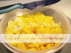 a bowl filled with cut up mangos next to a knife