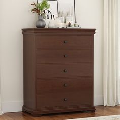 a brown dresser with two vases on top of it next to a white curtain