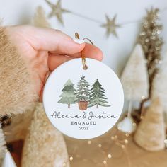 a hand holding a personalized ornament with trees on the front and back