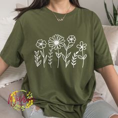 Wildflower Shirt, Wild Flower shirt, Wild flowers T-shirt, Floral Shirt, Flower T shirt, Botanical gift for her, birthday gift for her, flower graphic tee shirt for women, mothers day outfit, gift for mom, Boho Wildflower nature shirt, botanical shirt You select the size and color of your shirt.  There is a photo showing you the shirt colors. *Note the difference between solid colors and heather colors. The shirt colors available for the listing you are looking at will be in the drop-down menu. The shirts used are adult Bella+Canvas 3001 Unisex shirts. They are of a soft and lightweight fabric. The shirts are unisex, they are not a women's fitted style. Please refer to the sizing info/measurements so that you can order the correct size. We do not accept returns or exchanges. Please note th Green Floral Print Tops With Relaxed Fit, Short Sleeve T-shirt With Daisy Print For Spring, Spring Daisy Print Short Sleeve T-shirt, Green Floral Print Short Sleeve Top, Spring Green T-shirt With Floral Embroidery, Green T-shirt With Floral Embroidery For Spring, Green Floral Embroidery T-shirt For Spring, Green Short Sleeve Tops With Plant Print, Green Floral Embroidered T-shirt For Spring