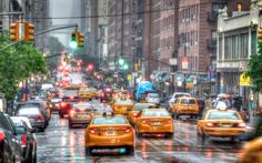 a city street filled with lots of traffic and yellow cabs driving down the road