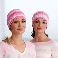 two women wearing knitted hats and pink sweaters posing for the camera with their heads together