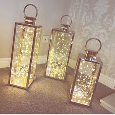 three lighted lanterns sitting on top of a carpet