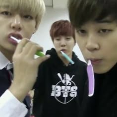 three young men brushing their teeth with toothbrushes