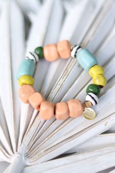 a close up of a bracelet on top of a white fan with two different colored beads