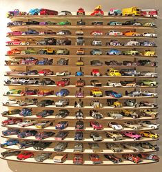 a shelf filled with lots of toy cars on top of wooden shelves next to a wall