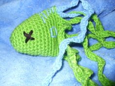 a crocheted green fish laying on top of a blue blanket