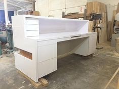 a white desk with drawers in a room full of wood and other items on the floor