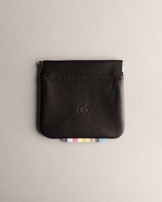 a small black leather wallet sitting on top of a white table next to a gray wall