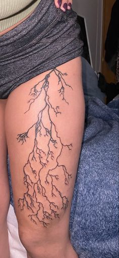 a woman's thigh with a tree tattoo on it