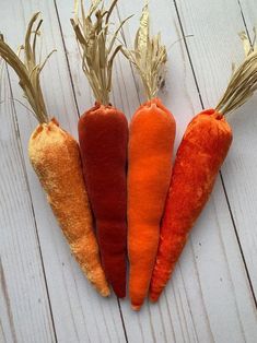 four carrots are lined up on a white wooden surface, one is orange and the other is red