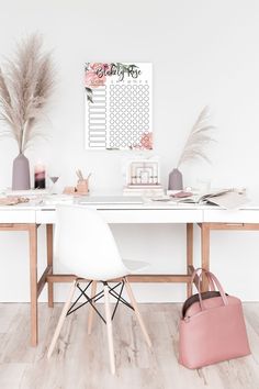 a white table topped with a pink bag next to a vase filled with pamodia