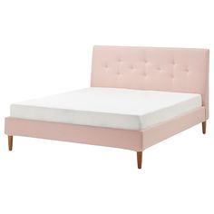 a pink bed with white sheets and wooden legs