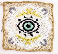 a crocheted square with an eye in the center and two circles around it