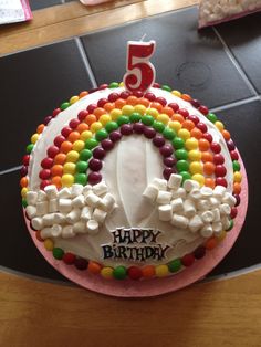 a birthday cake with the number five on it, decorated in rainbows and marshmallows