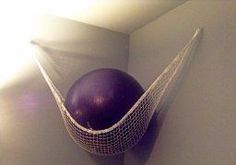 a purple ball in a white net hanging from the side of a wall with sunlight coming through it