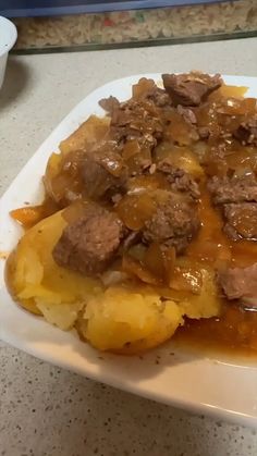 a white plate topped with meat and potatoes covered in gravy