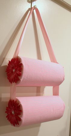 two red flowers are hanging from a pink ribbon on the wall next to a light fixture