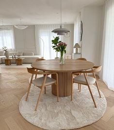 a round wooden table with four chairs around it in a living room next to a couch