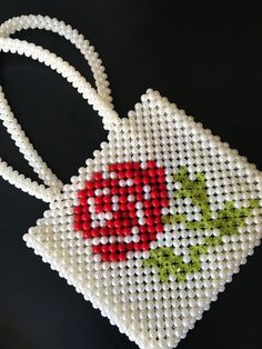 a cross stitch bag with a red flower on the front and green leaves on the back