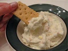 a cracker is being dipped into a bowl of ice cream on a black and white plate