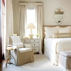 a bedroom with a bed, chair and mirror on the wall next to two windows