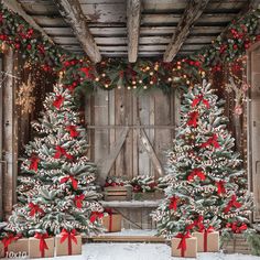 two christmas trees with presents under them in front of a barn door decorated for the holidays