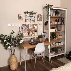 a desk with some plants and pictures on the wall