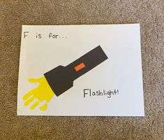 a piece of paper that says f is for flashlight on it with an orange hand sticking out of it