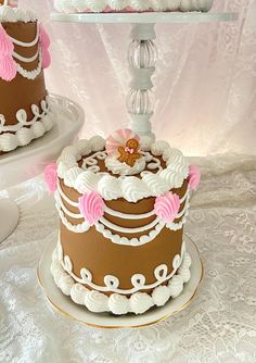 two tiered cakes with pink and white icing on them sitting on a table