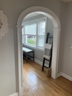 an archway leading into a living room with hard wood floors and white trim on the walls