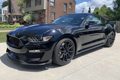 a black mustang parked in front of a house